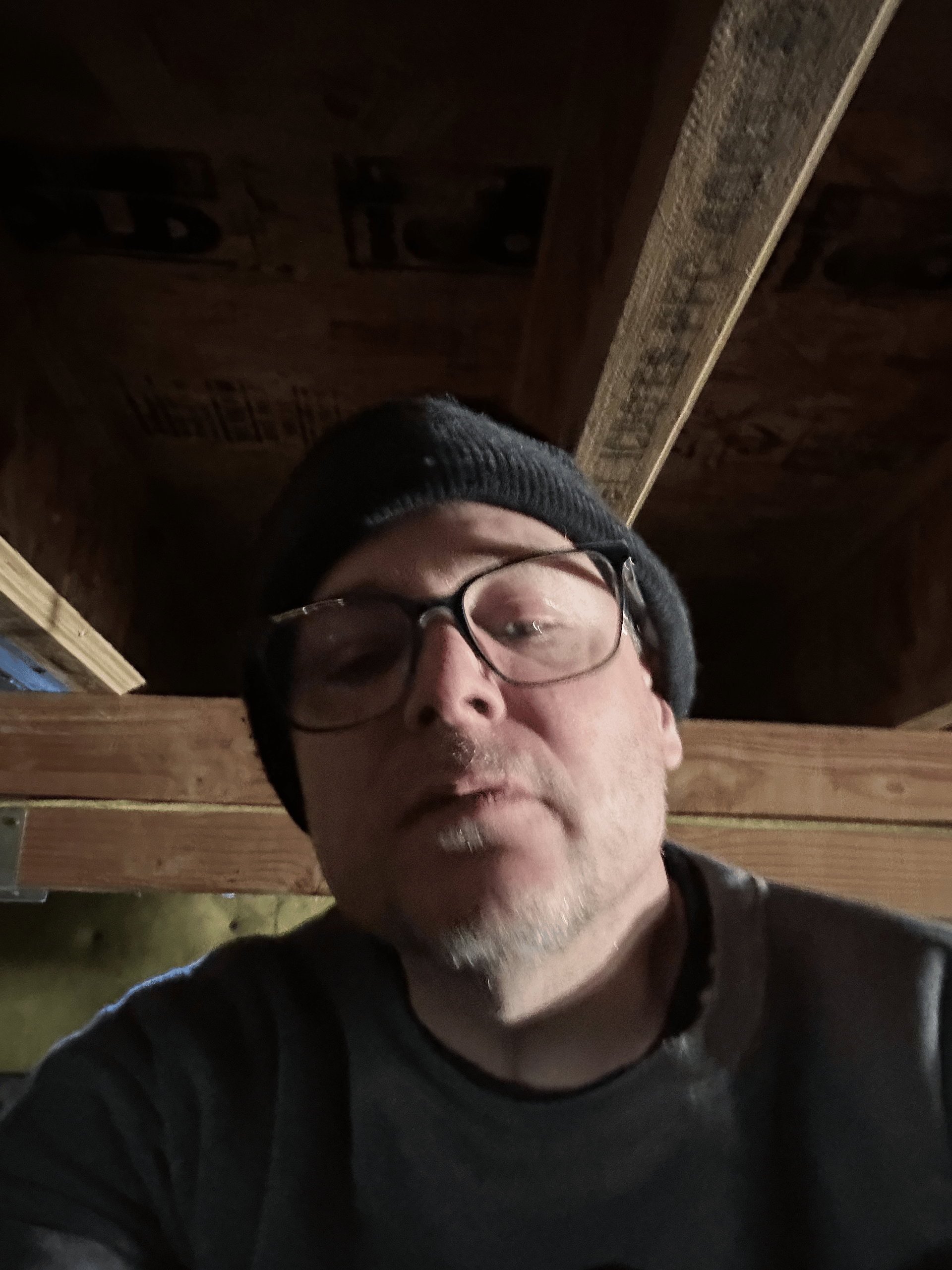 A man wearing glasses and a beanie is looking at the camera.