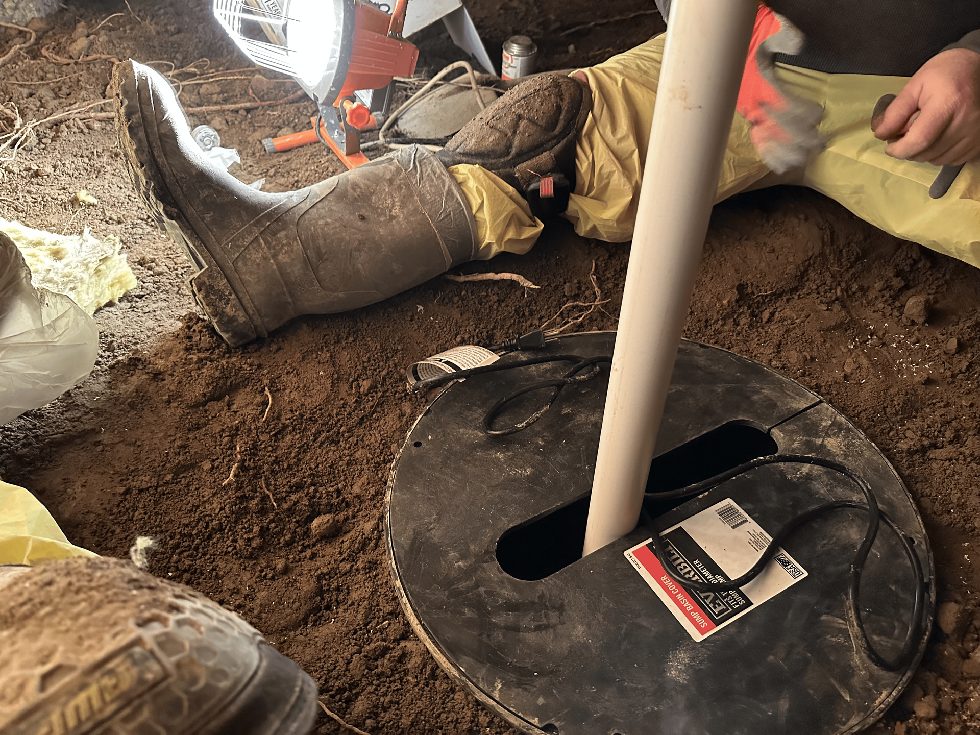 A person is laying in the dirt next to a lamp.