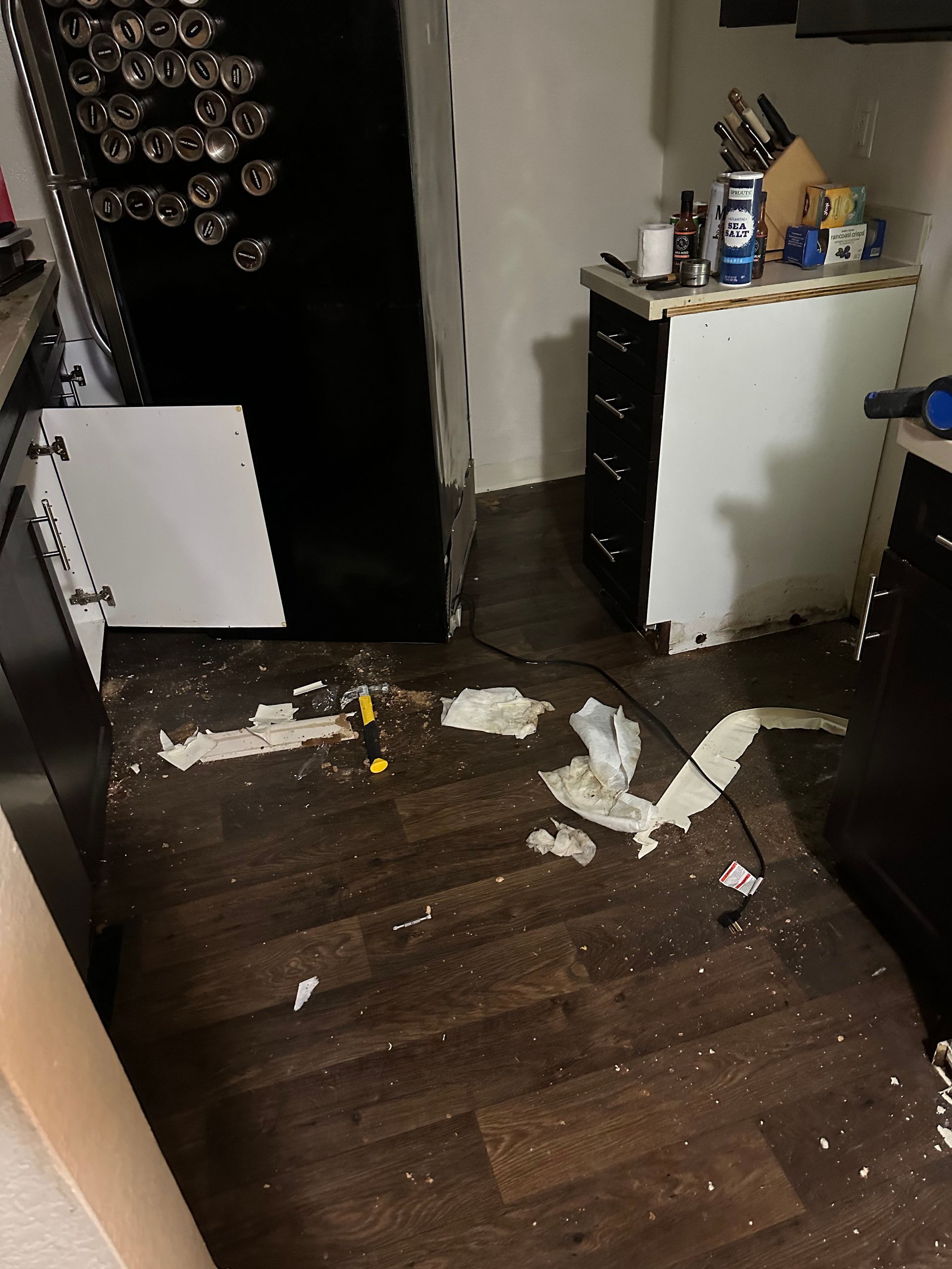 A kitchen with a broken refrigerator and a broken cabinet