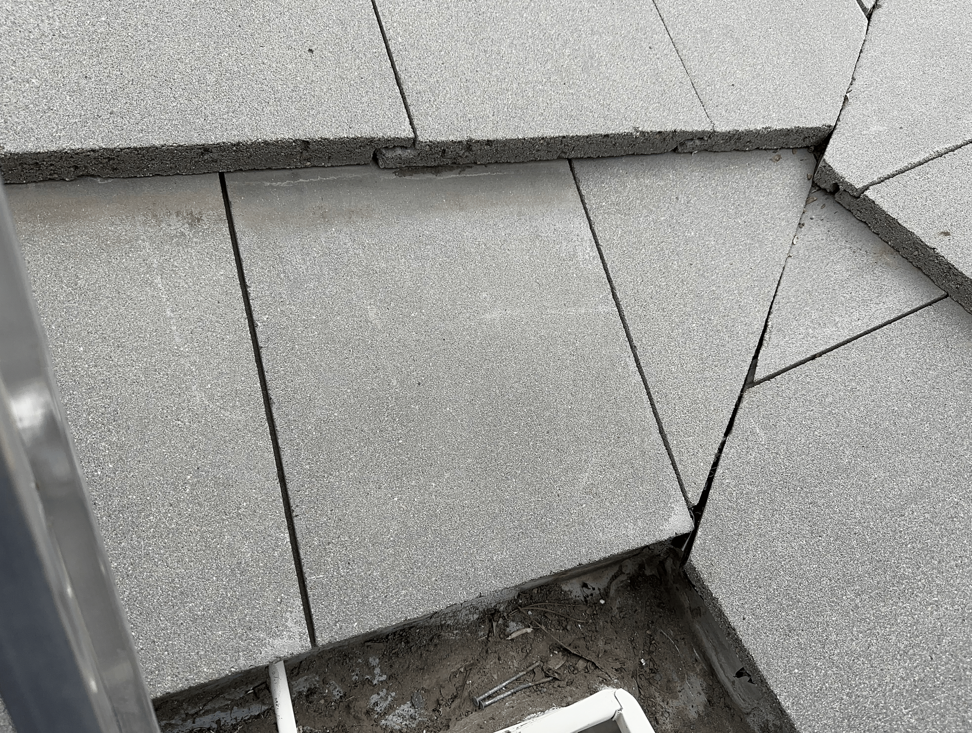 A close up of a gray tile floor with a ladder in the background.