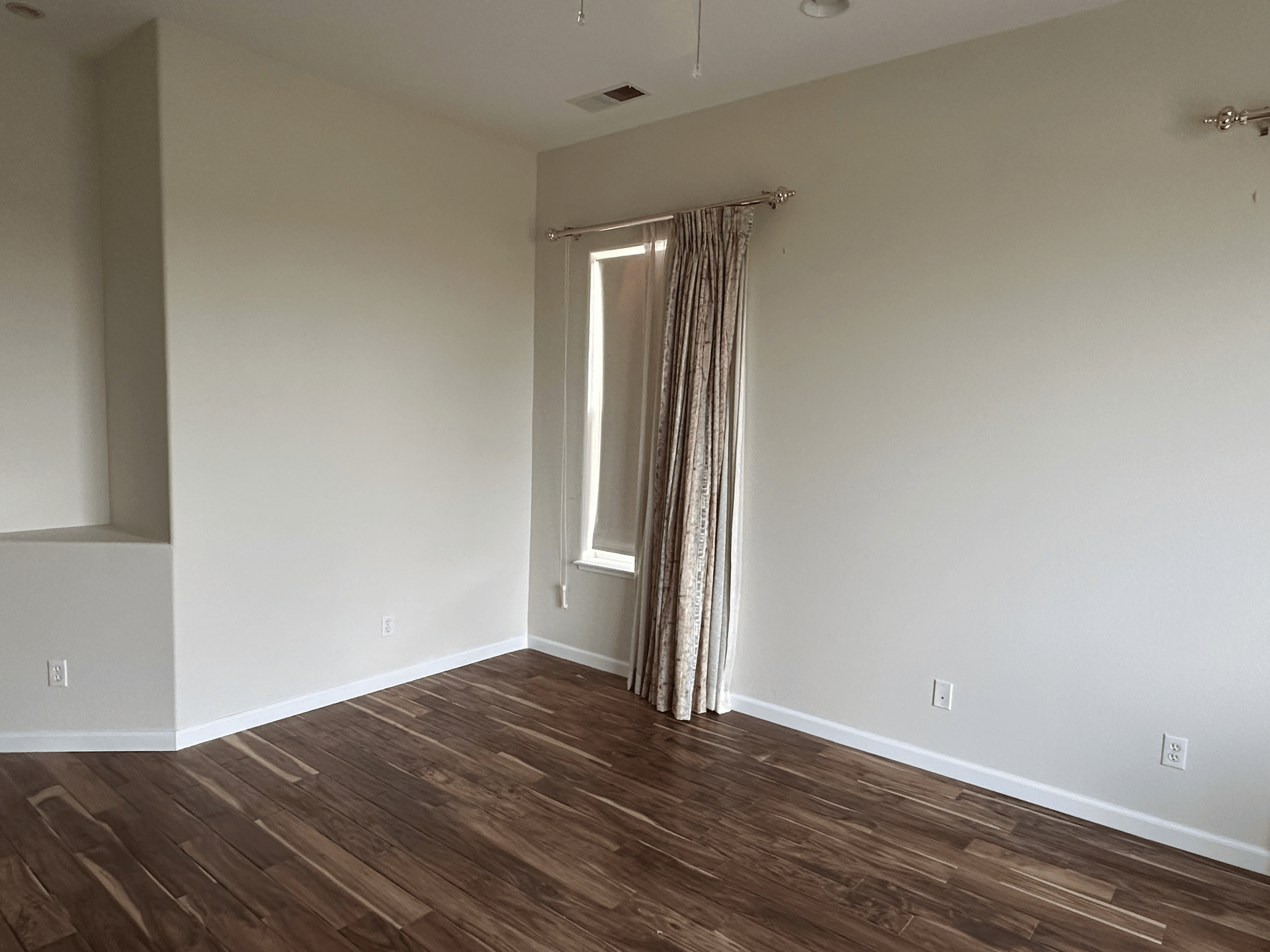 An empty living room with hardwood floors and a window.