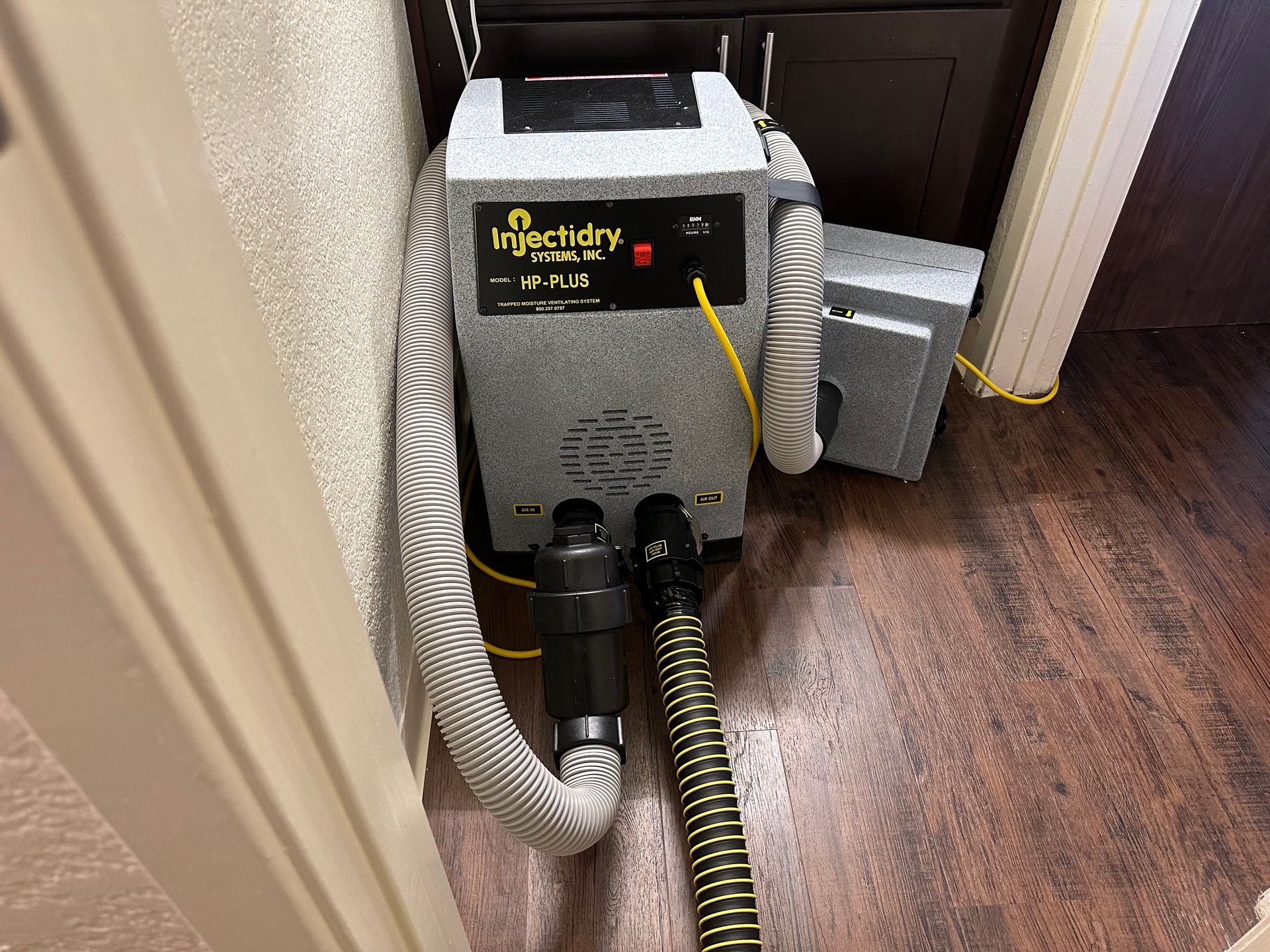 A vacuum cleaner is sitting on a wooden floor next to a door.
