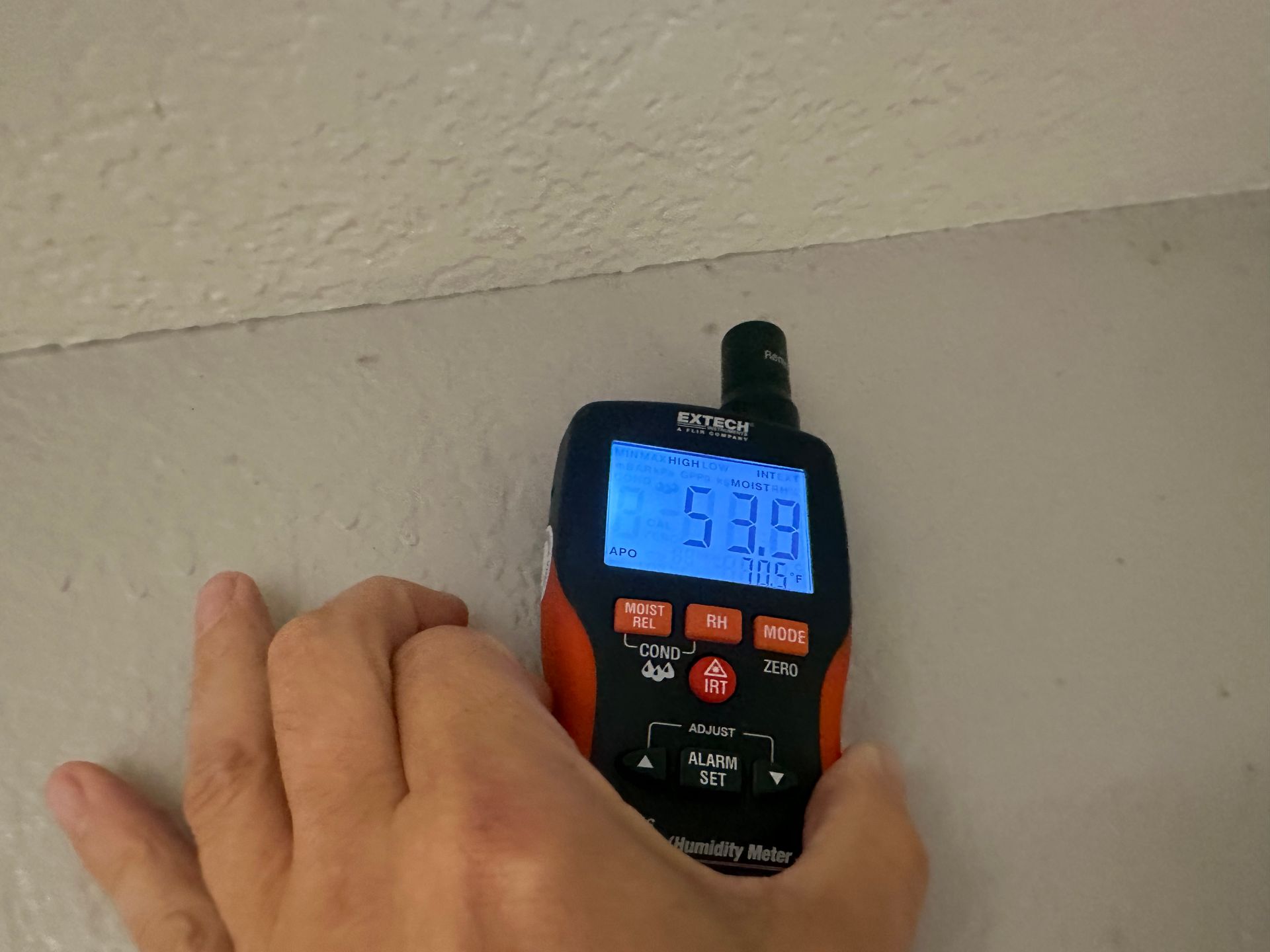 A person is measuring a wall with a digital device.