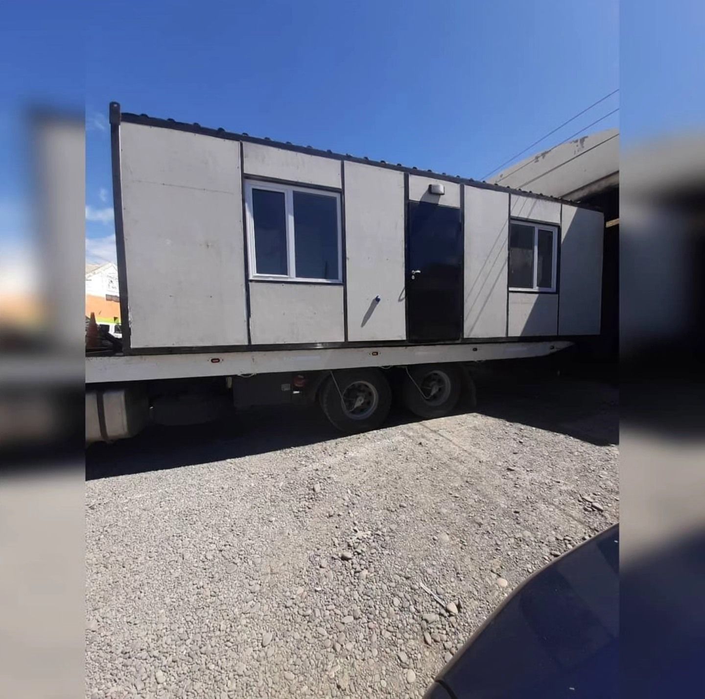 Un remolque con una casa encima está estacionado en un lote de grava.