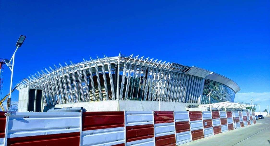 Un gran edificio en construcción con una valla roja y blanca delante.