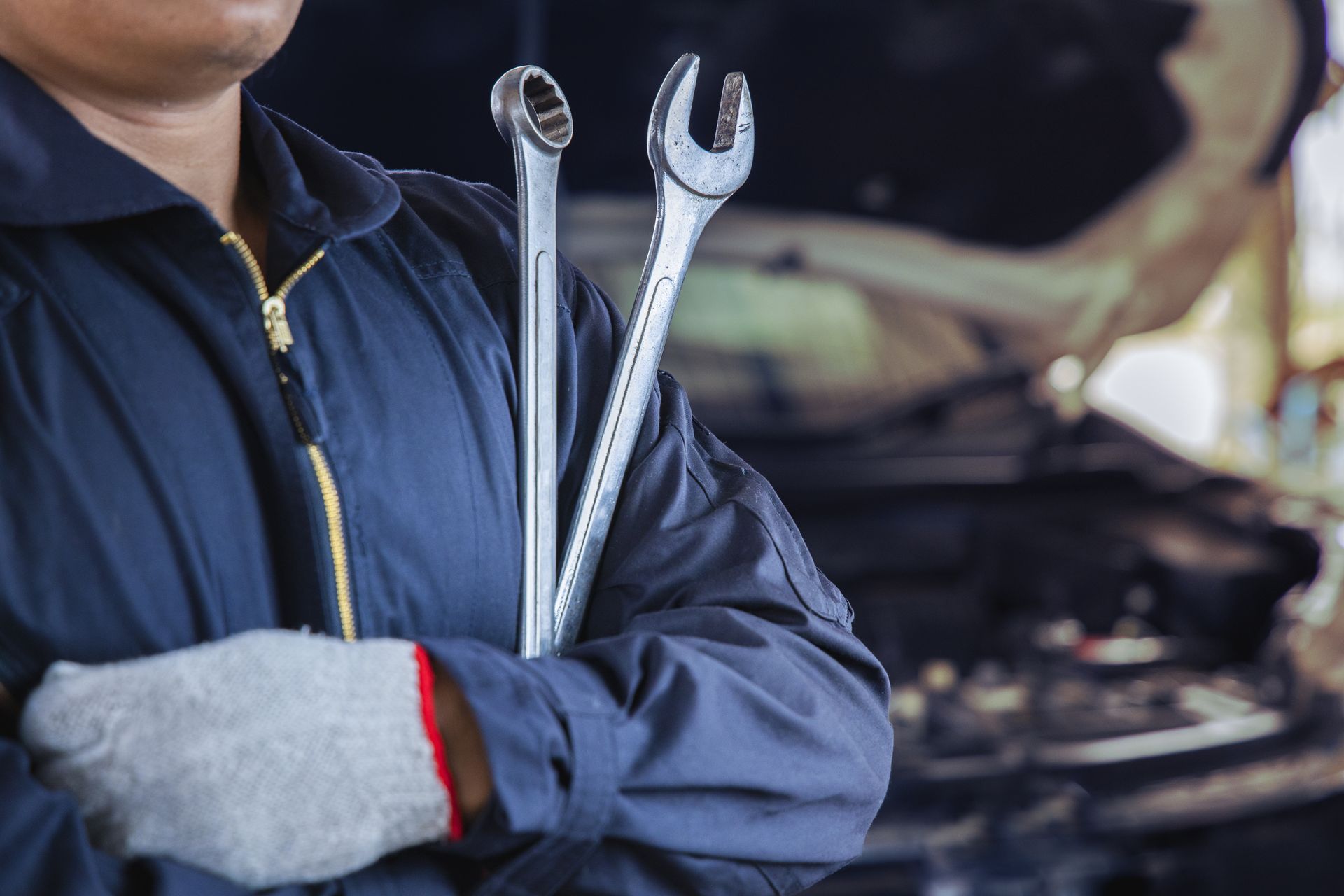 Auto technician holding wrenches near open vehicle hood during professional car repair service
