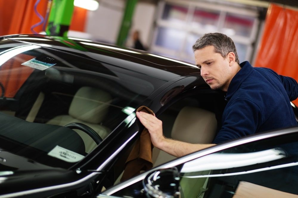 A Man Is Cleaning The Windshield Of A Car In A Garage — Rocky Car Wash In Berserker, QLD