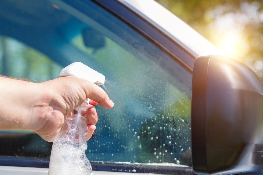A Person Is Cleaning The Windshield Of A Car With A Spray Bottle — Rocky Car Wash In Berserker, QLD