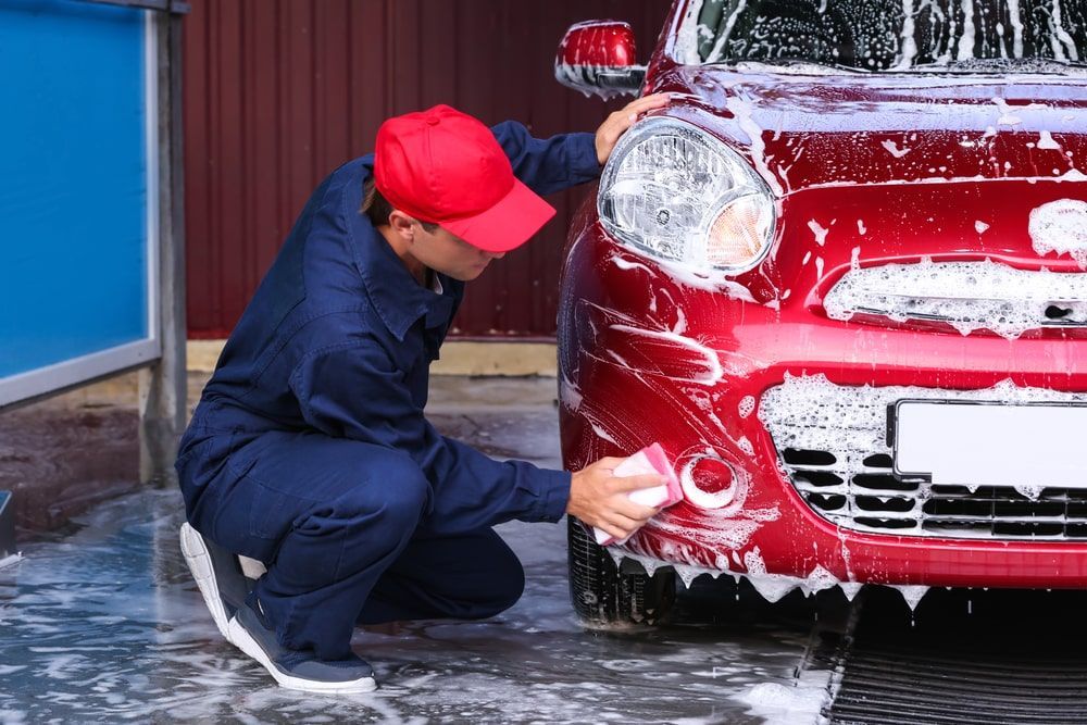 A Man Is Washing A Red Car At A Car Wash — Rocky Car Wash In Berserker, QLD