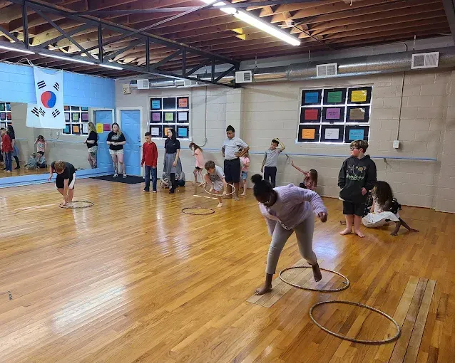 A group of children are playing with hula hoops in a dance studio.