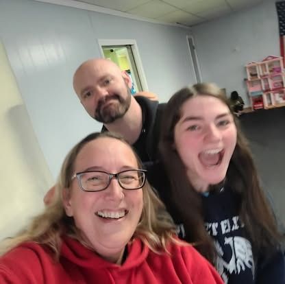 A man and two women are posing for a selfie in a room.