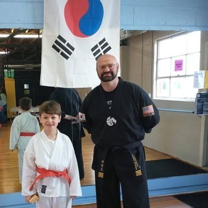 A man and a boy pose in front of a korean flag