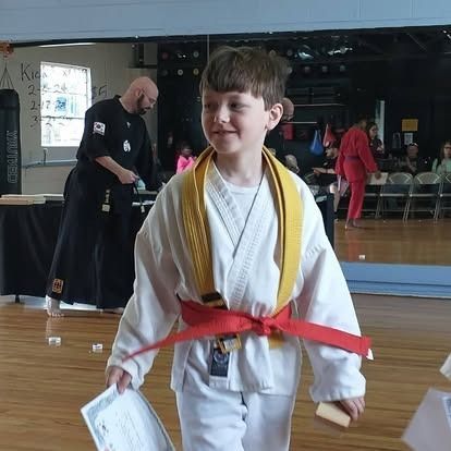A young boy in a white karate uniform with a red belt
