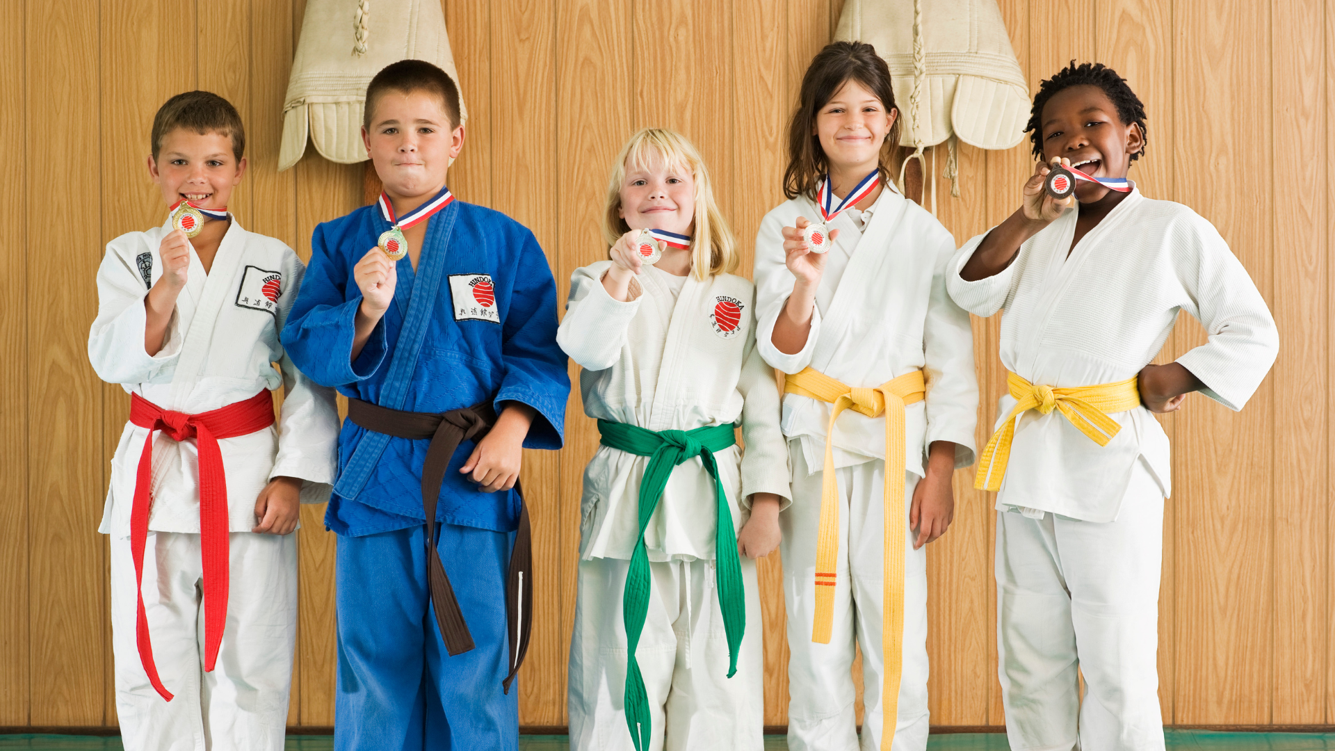 A group of children are standing next to each other holding medals.