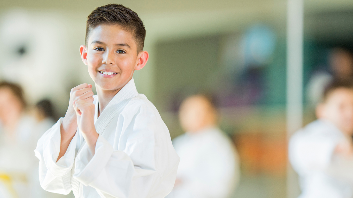 A young boy is practicing karate in a gym.