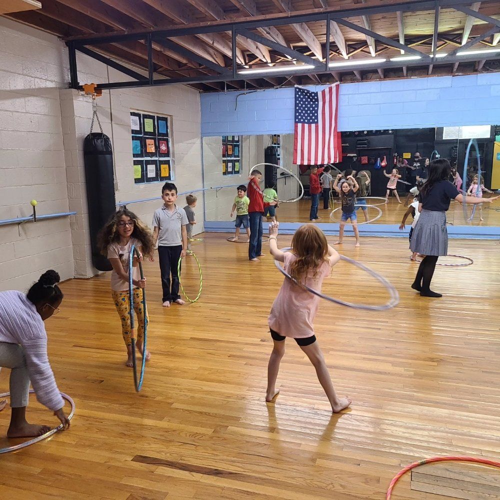 A group of children are playing with hula hoops in a gym