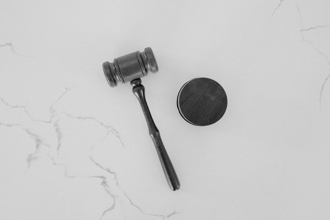 Black and white image of a gavel and sound block on a white marble surface.