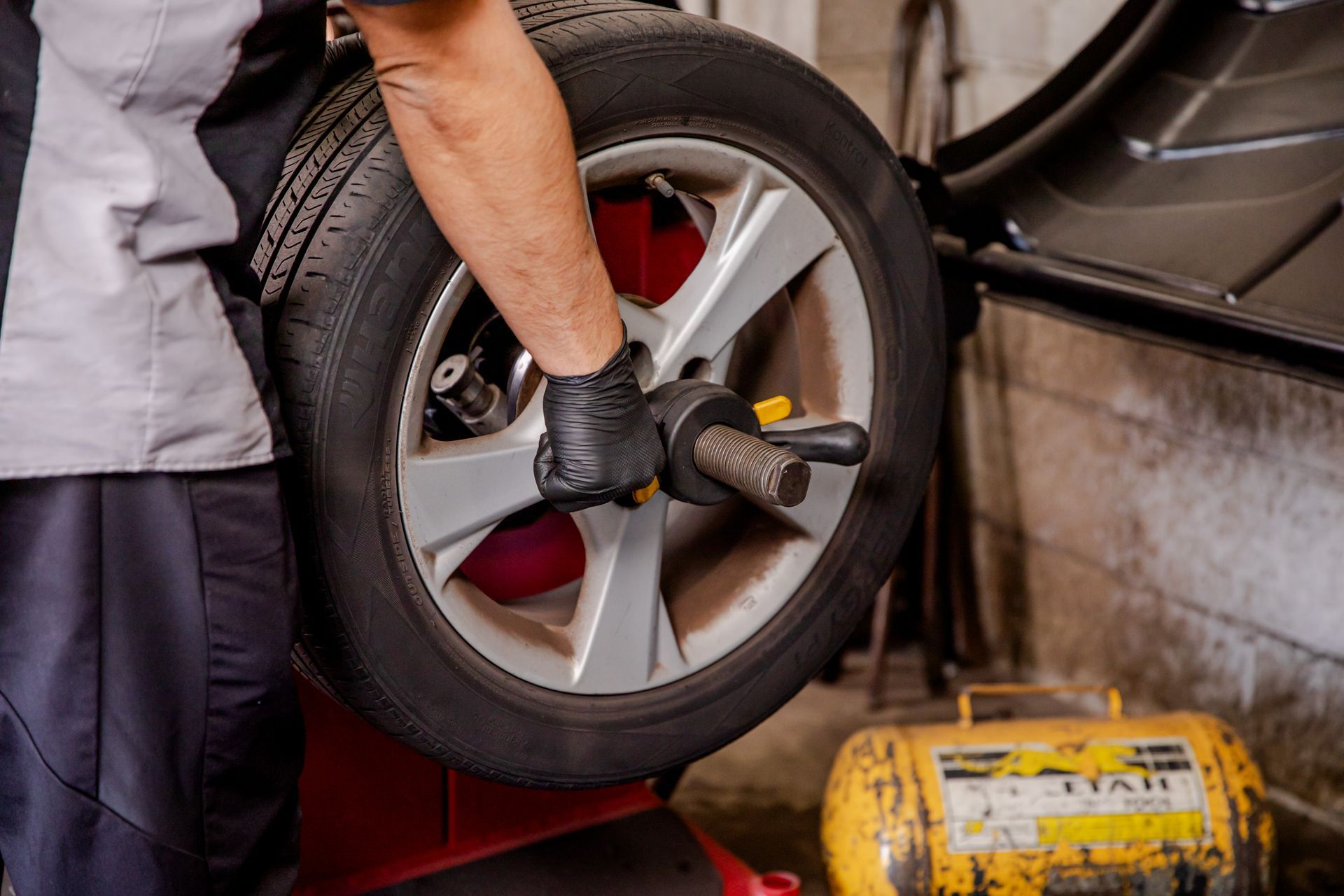 A man is adjusting a tire on a truck in a auto shop.