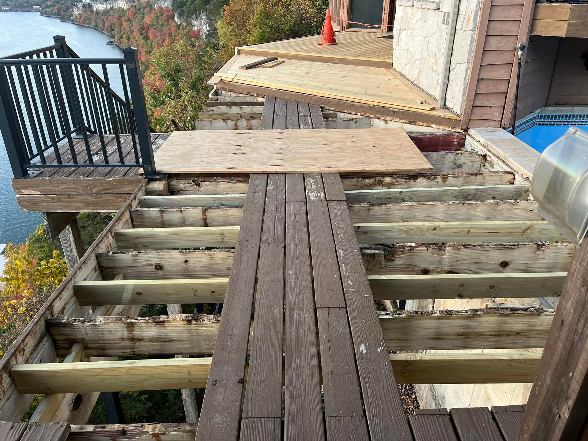 Wooden deck overlooking a lake and fall foliage from a house built into a hillside.