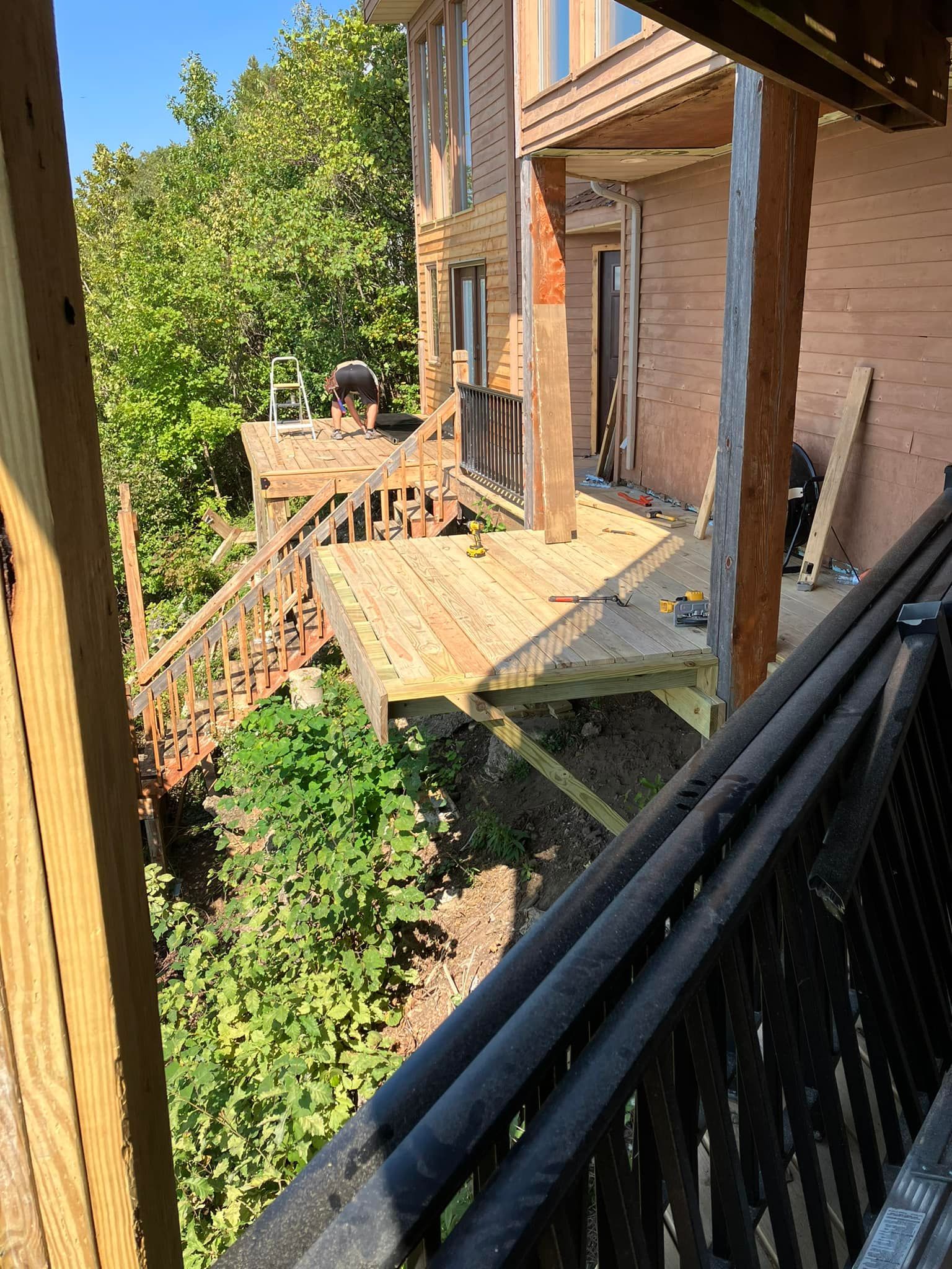 Deck built onto a multi-story brick building. Deck is made of wood, has stairs, and overlooks greenery.