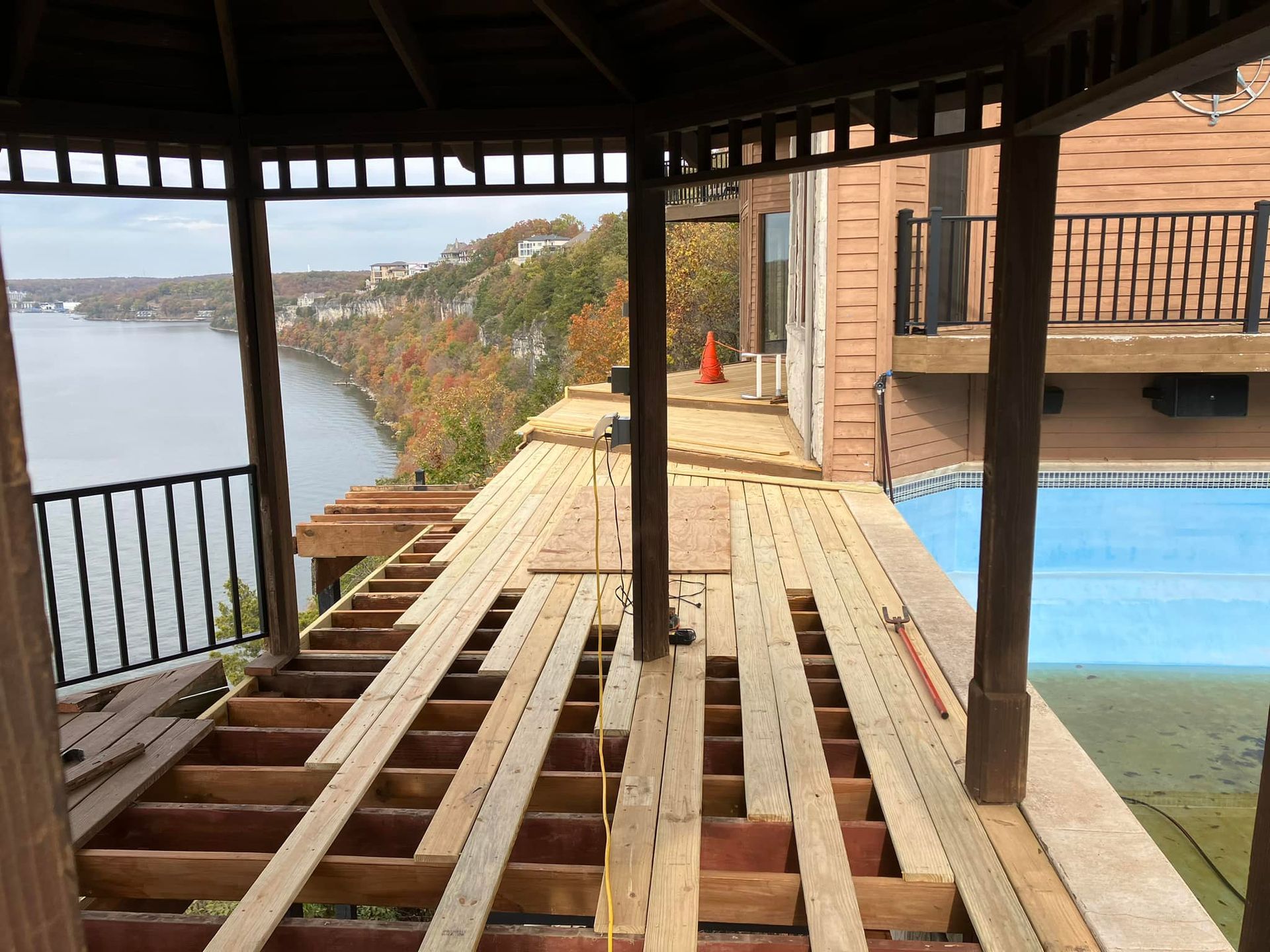 Deck renovation: wood planks being laid over support beams, overlooking a body of water.