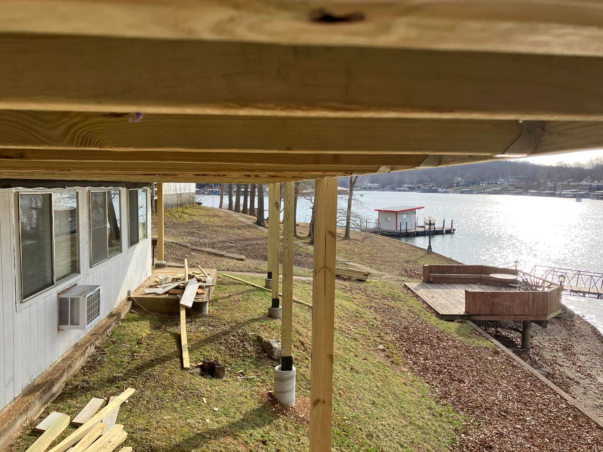 Deck overlooking a lake, with wooden posts supporting the structure.