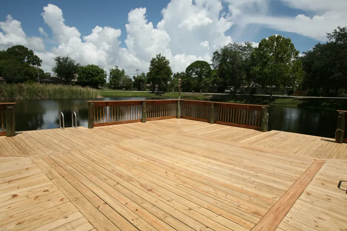 Man takes a selfie while two others paint a wooden deck green.