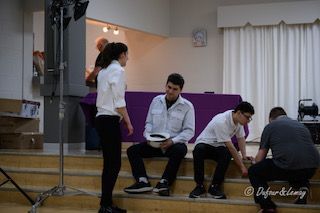 Un groupe de personnes sont debout et assises sur les marches d'une pièce.