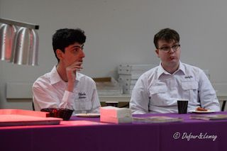 Deux hommes sont assis à une table avec des assiettes de nourriture.
