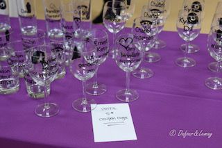 Un tas de verres à vin sont posés sur une table violette.
