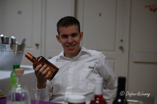 Un homme en chemise blanche tient une bouteille de whisky.
