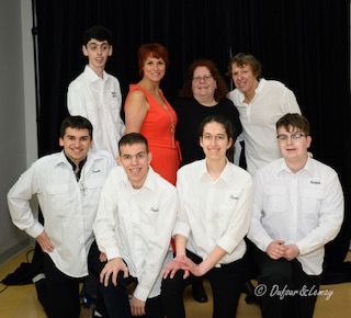 Un groupe de personnes posant pour une photo avec une femme en robe rouge