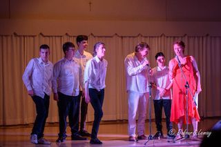 Un groupe de personnes se tient sur une scène et tient des microphones.