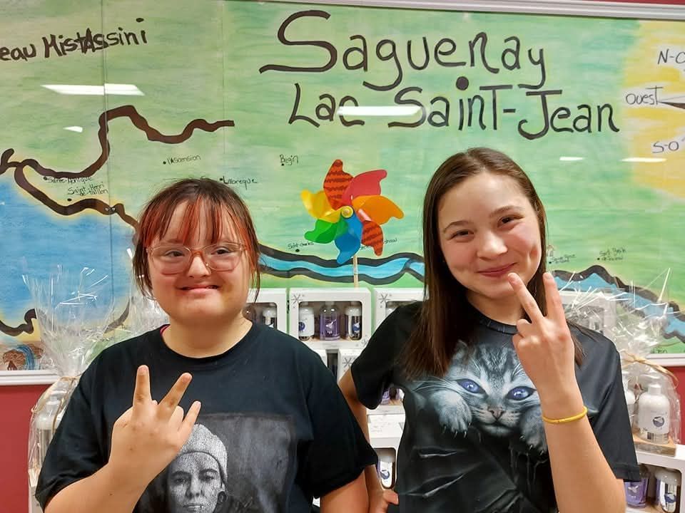 Deux filles se tiennent devant un panneau indiquant Saguenay Lac Saint-Jean