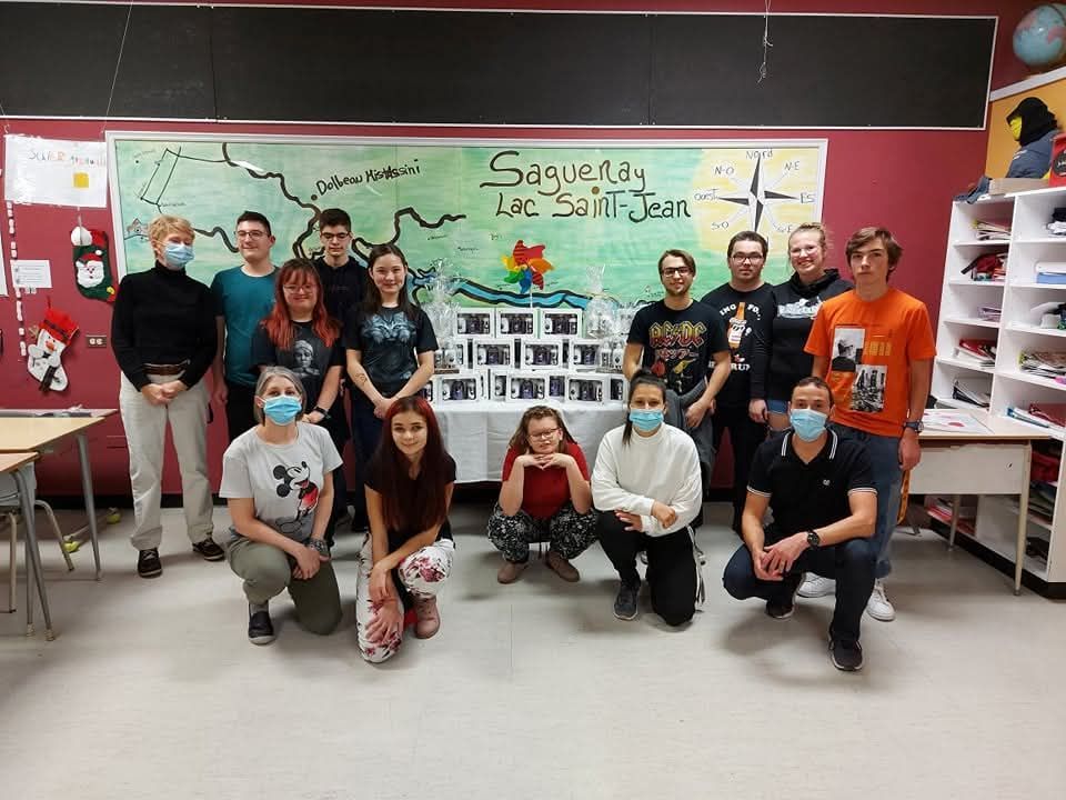 Un groupe de personnes portant des masques posent pour une photo dans une salle de classe.