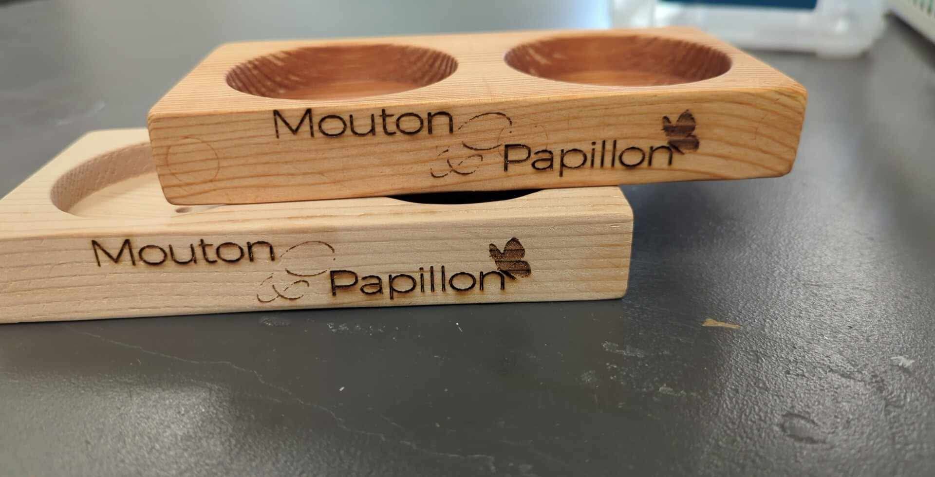 Deux blocs de bois avec les mots mouton papillon gravés dessus sont empilés l'un sur l'autre sur une table.