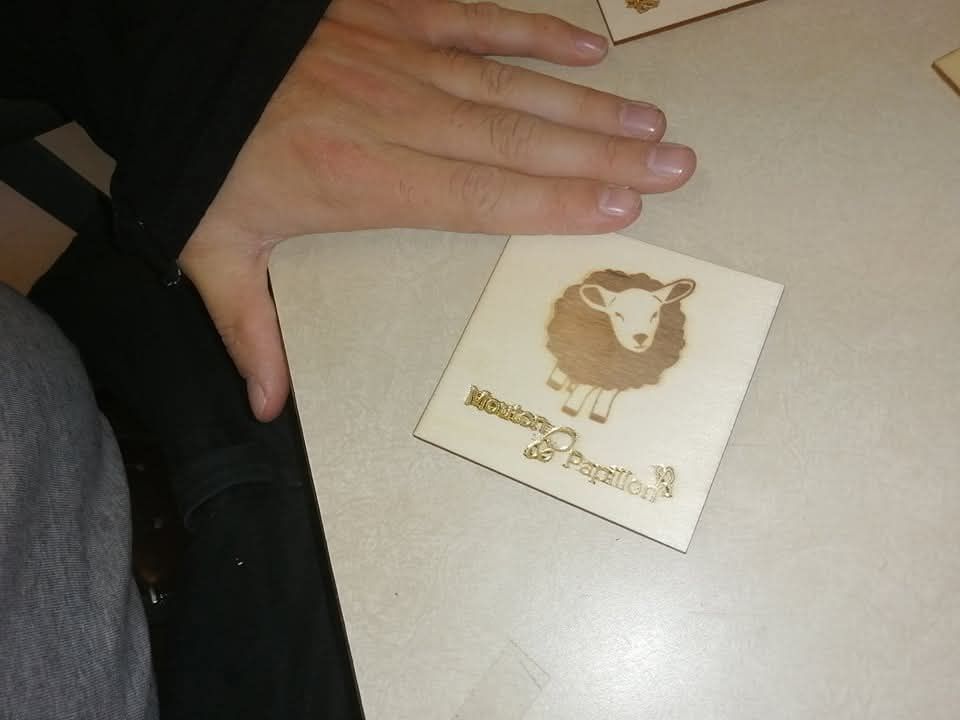 Une personne tient un sous-verre avec un mouton dessus