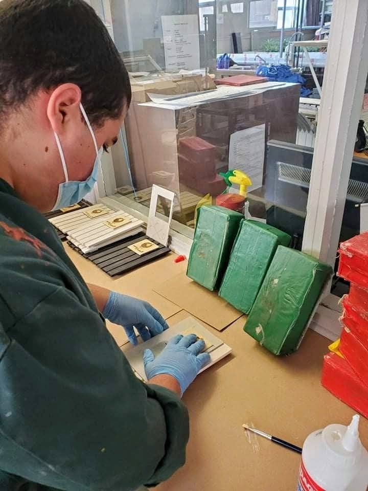 Un homme portant un masque et des gants est assis à une table.