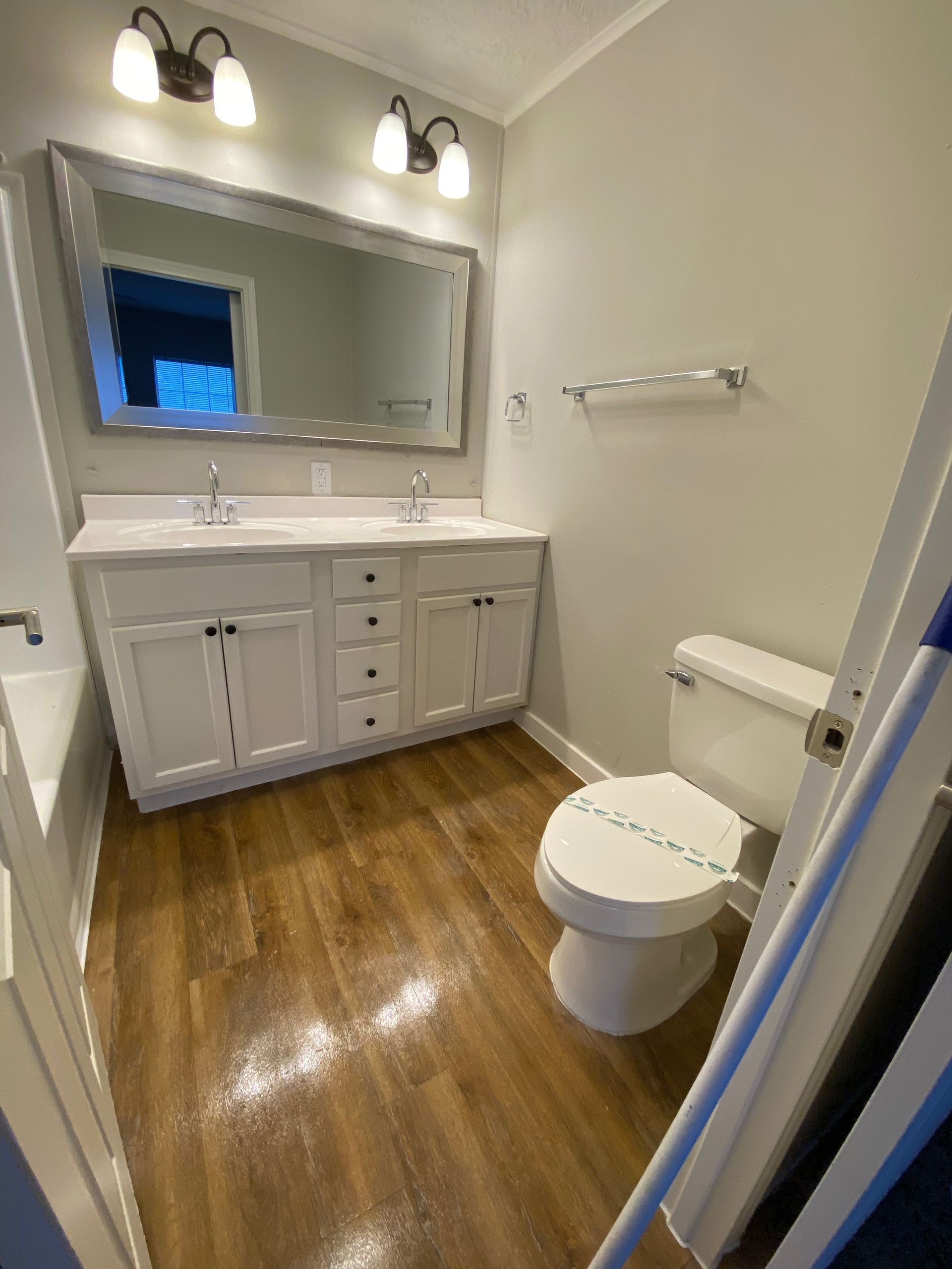 A bathroom with a toilet , sink and mirror.