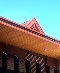 Edificio de ladrillo con un detalle de techo triangular rojo bajo un cielo azul brillante.