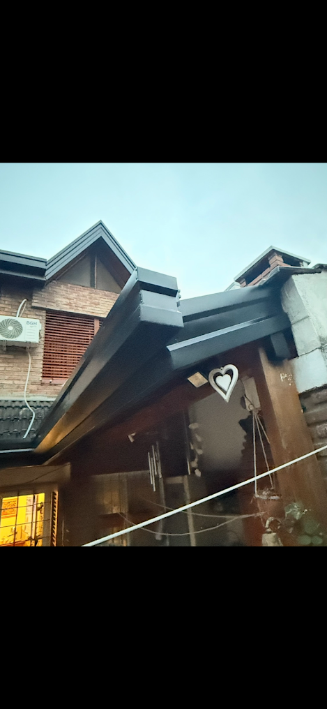 Exterior de una casa de madera con techo inclinado y porche en un día lluvioso.
