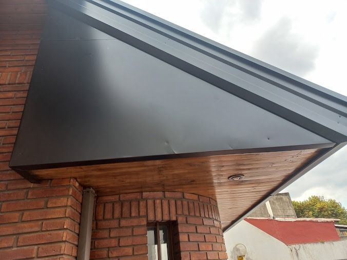Toldo negro sobre la entrada de un edificio de ladrillos bajo un cielo nublado.
