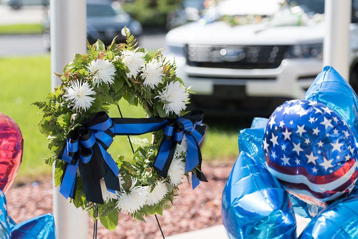 A wreath and balloons are sitting on a pole.