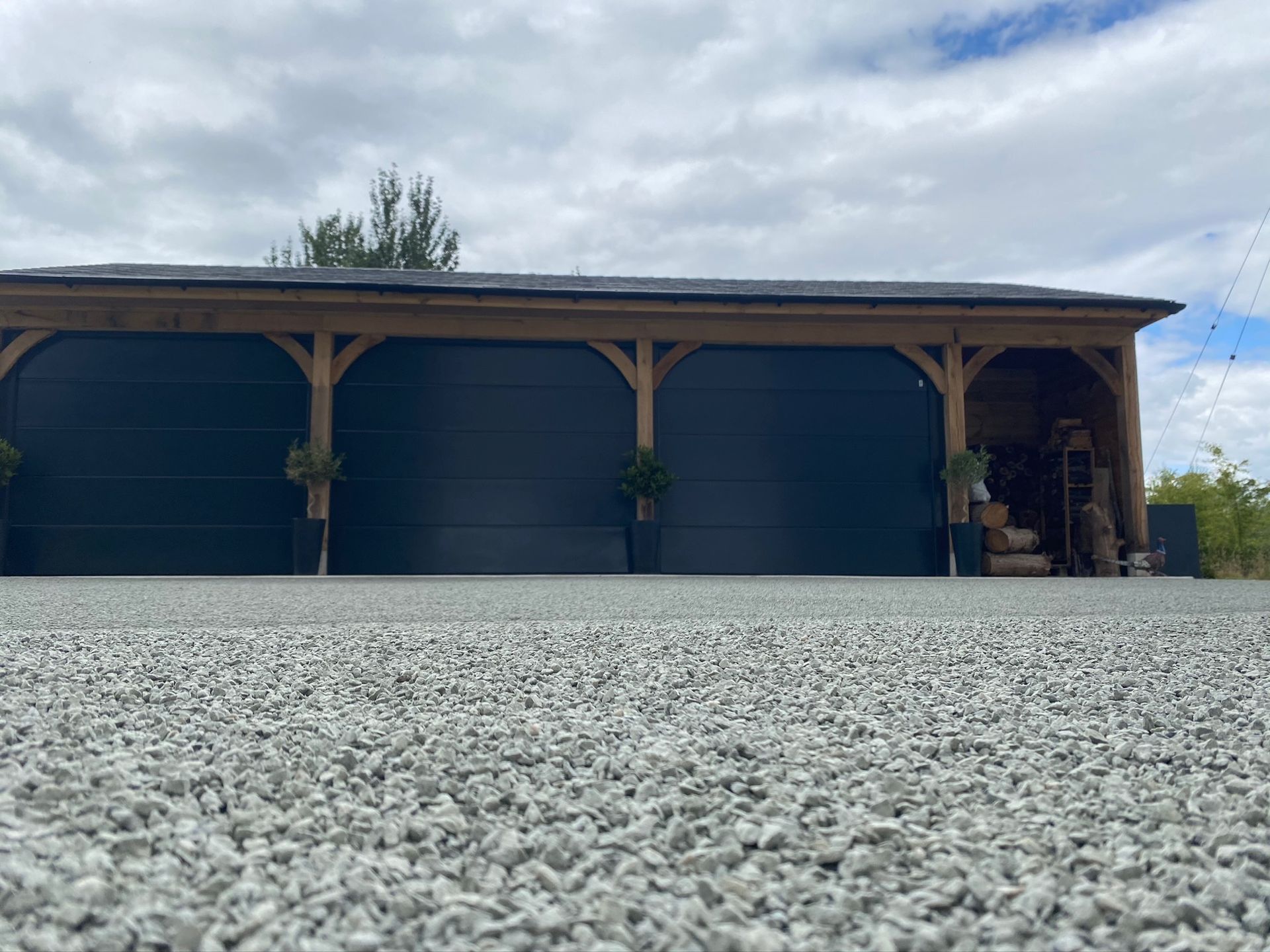 A garage with three doors is sitting on top of a gravel driveway.