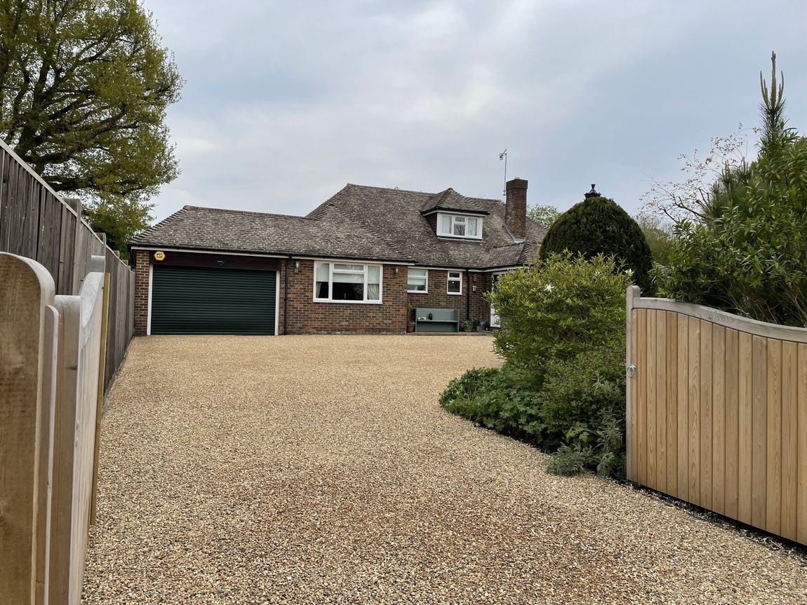 A house with a gravel driveway leading to it.
