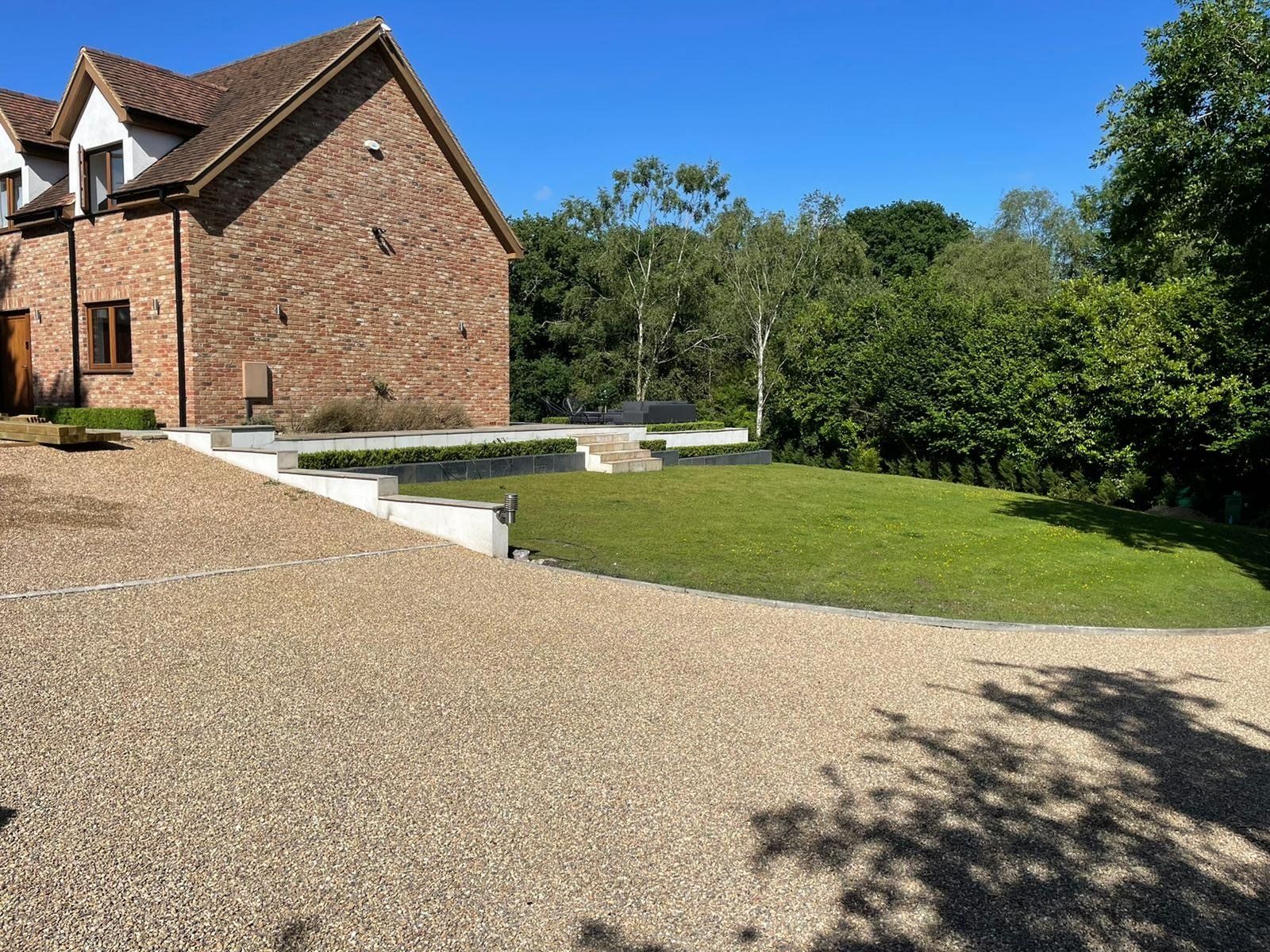 A large brick house with a gravel driveway in front of it.