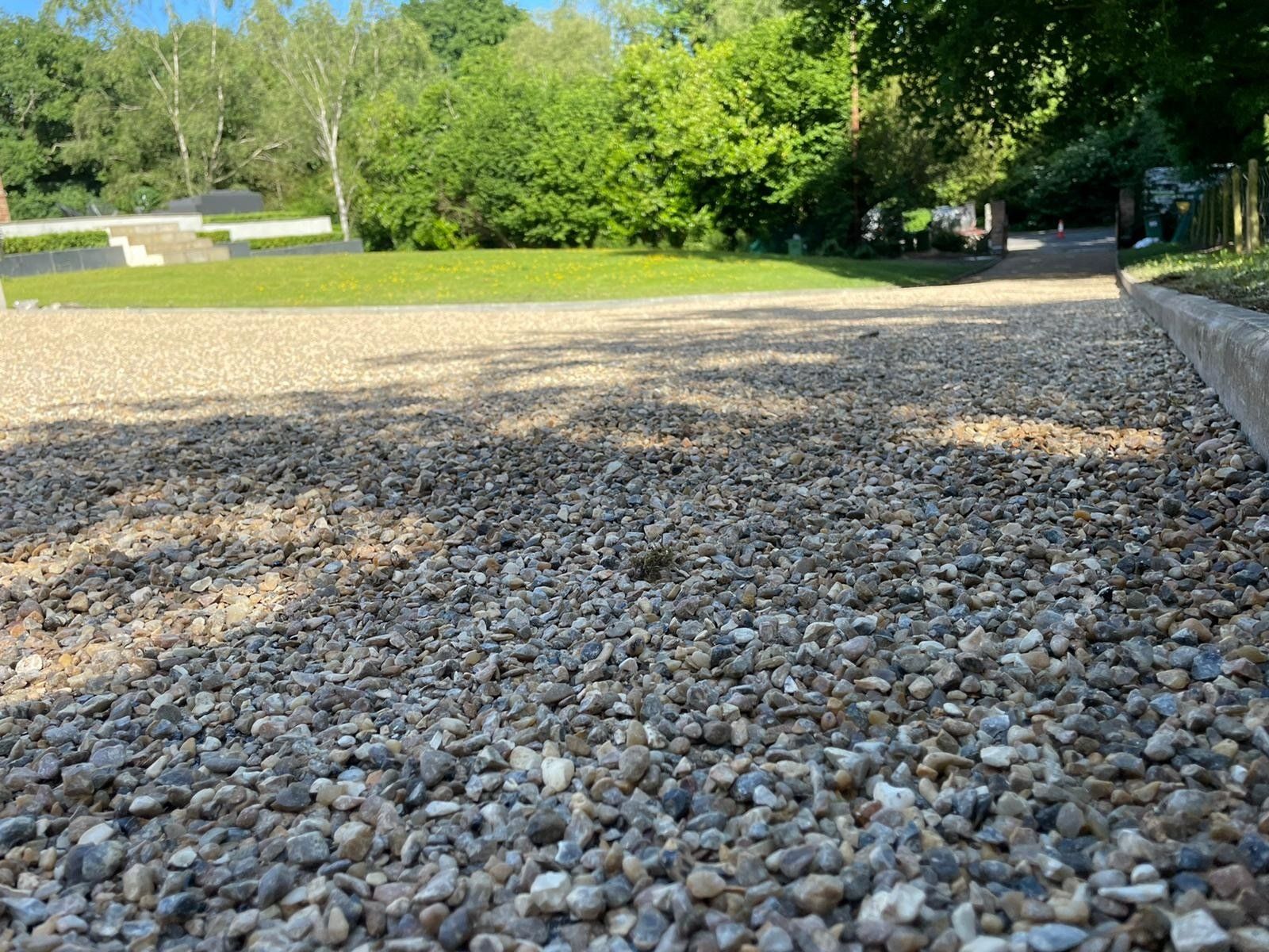 A gravel driveway with trees in the background.