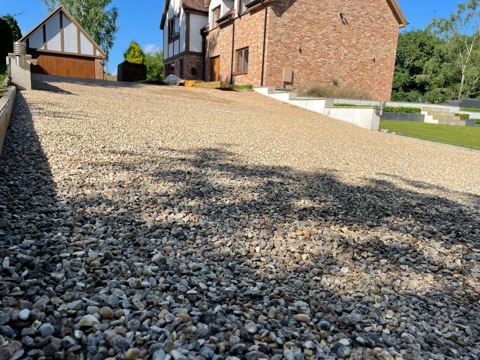 A golden sandy gravel driveway leading to a large brick house. Sussex