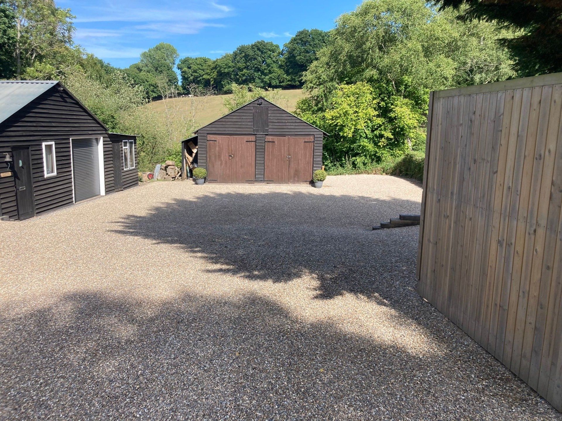 Two garages are sitting next to each other in a gravel driveway.