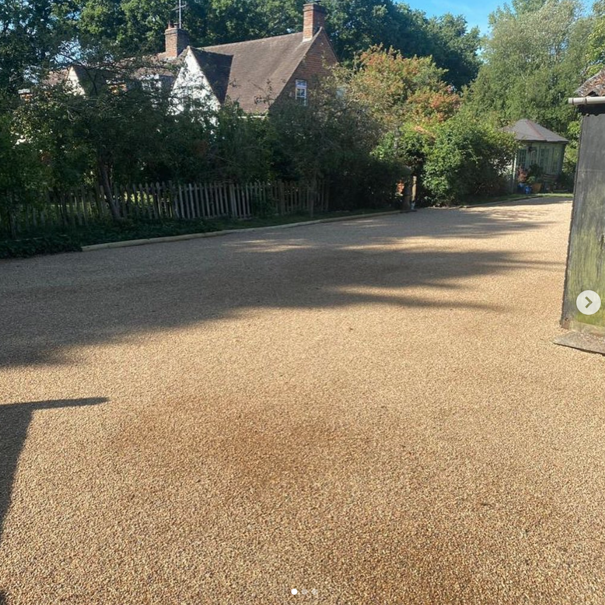 A gravel driveway with a house in the background.
